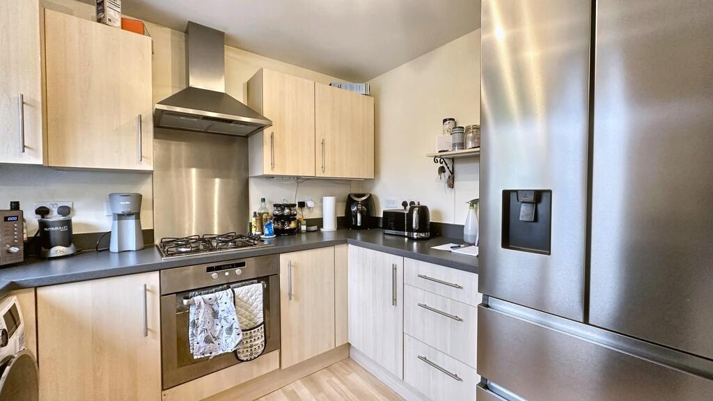 Modern fitted kitchen with light wood cabinets,...