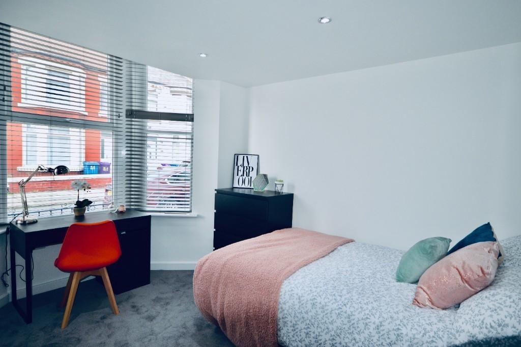 A bright and welcoming bedroom featuring a cozy...