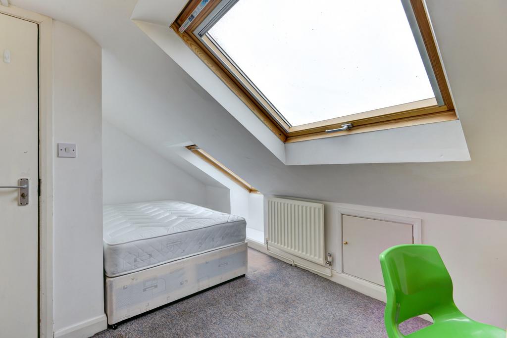 A bright, clean bedroom featuring a single bed,...