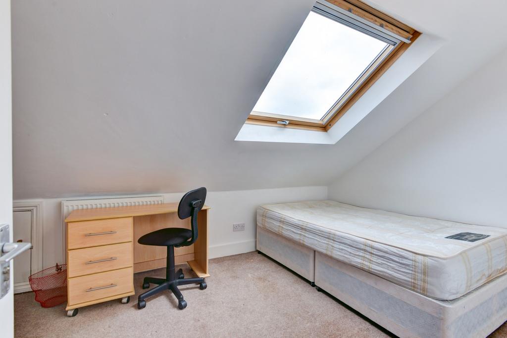 Bright attic bedroom with a sloped ceiling and ...