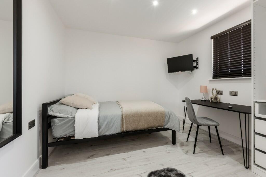A bright, neat single bedroom featuring a comfo...
