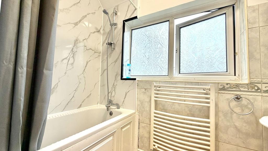 Bright, modern bathroom with a white bathtub, h...