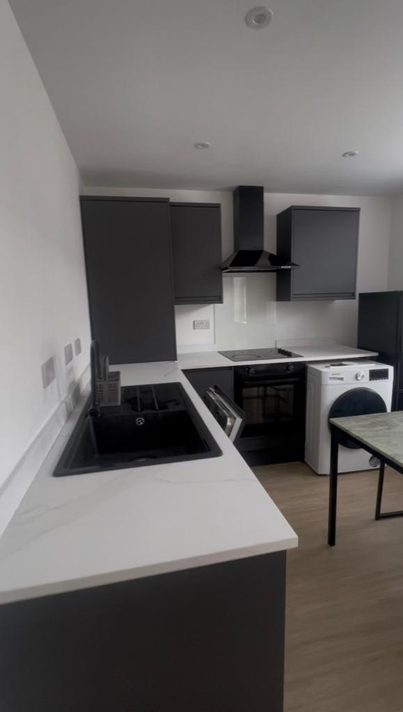 Modern kitchen with dark cabinetry, white marbl...