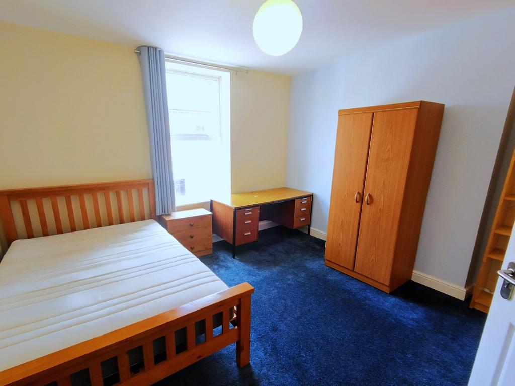 Bright, simply furnished bedroom with a wooden ...