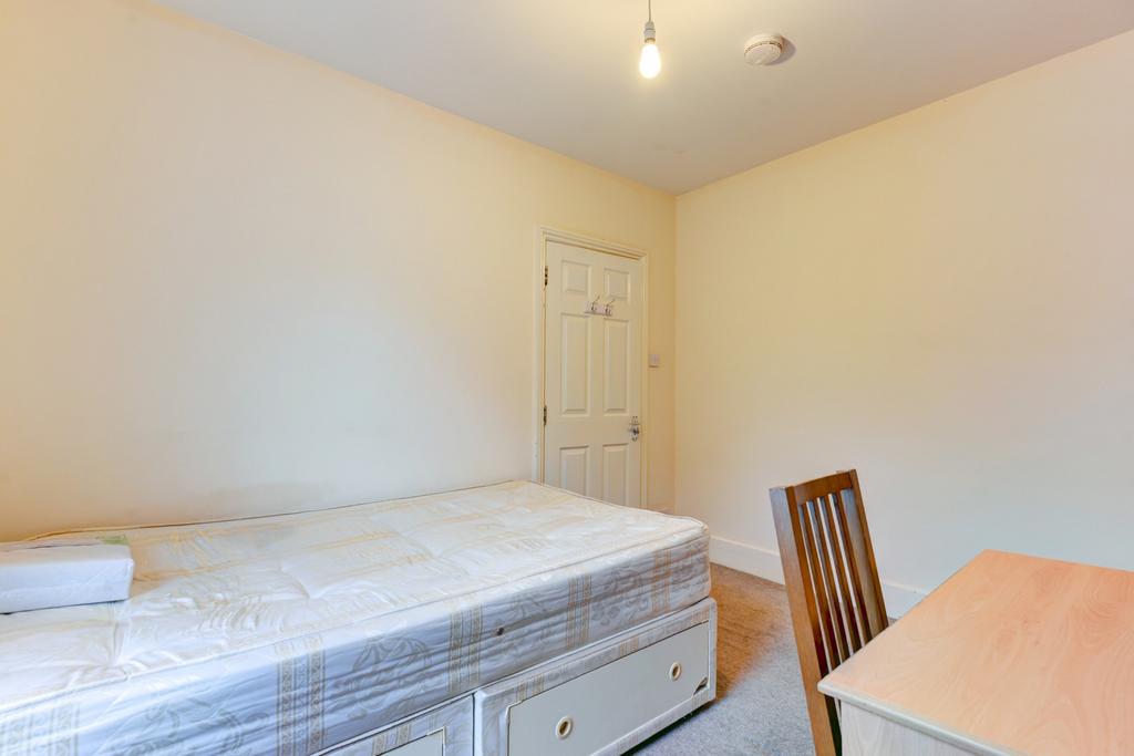 A bright and clean single bedroom featuring a s...
