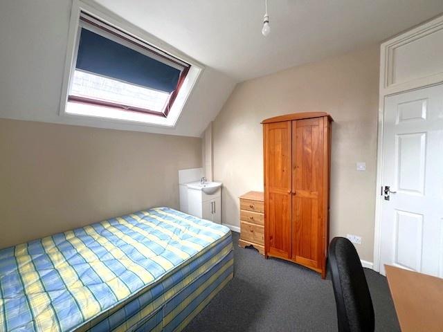 A tidy single bedroom featuring a bed with a st...