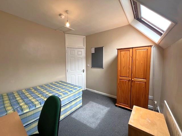 A modest bedroom featuring a single bed with a ...
