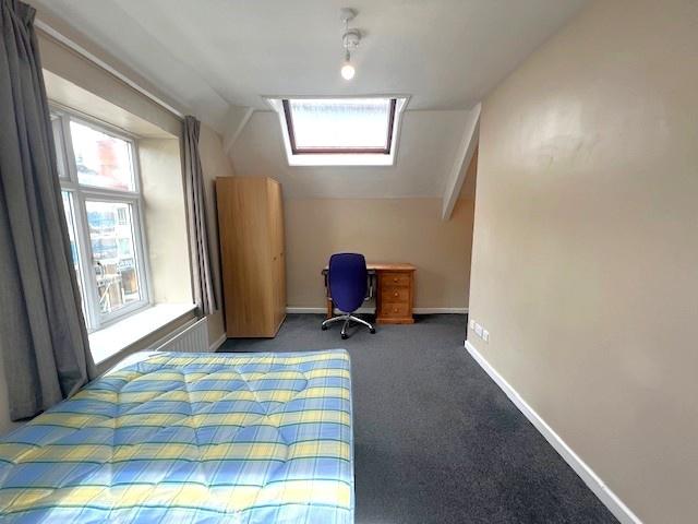 A well-lit bedroom featuring a comfortable bed,...