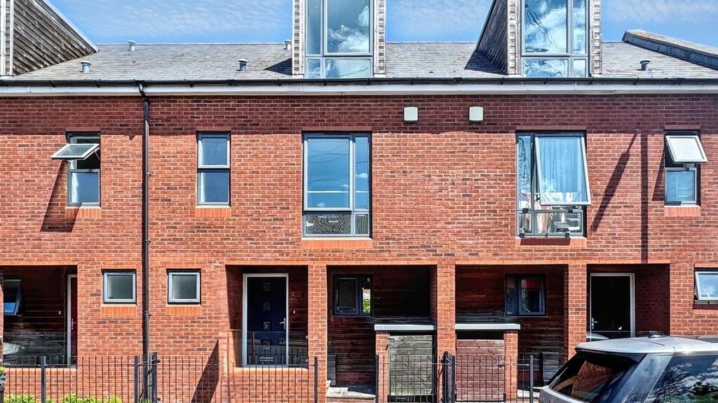 Modern red-brick terraced house façade with nea...