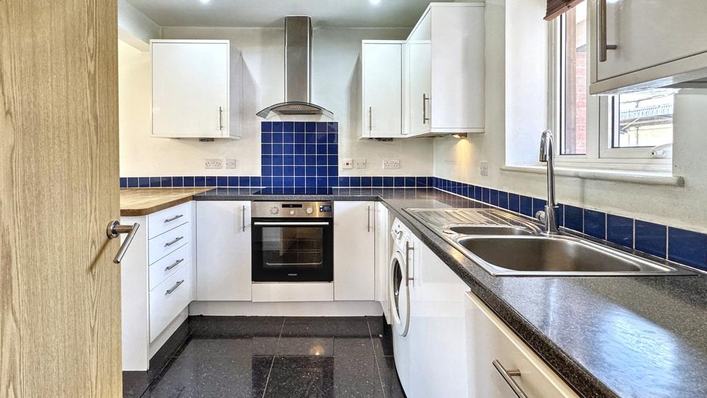 Bright modern kitchen with white cabinetry, blu...