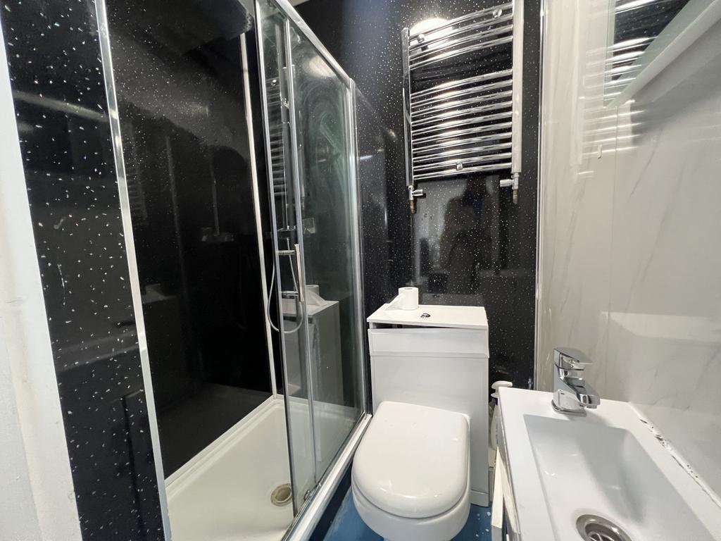 Modern compact bathroom with a glass-enclosed s...