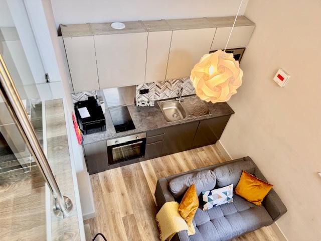 Modern open-plan kitchenette with sleek dark ca...