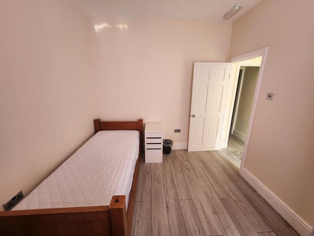 Simple, tidy single bedroom with a wooden bed f...