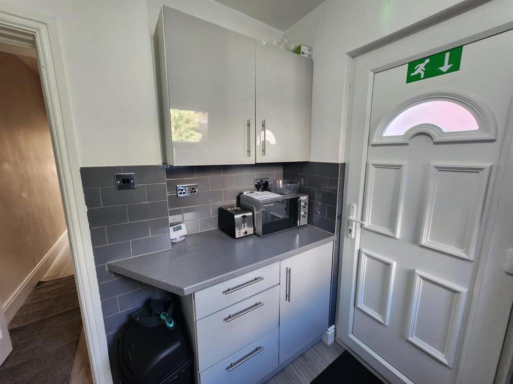 Compact, modern kitchenette with grey cabinetry...