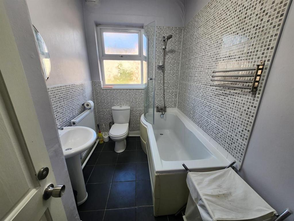 Modern bathroom with patterned tile walls, whit...