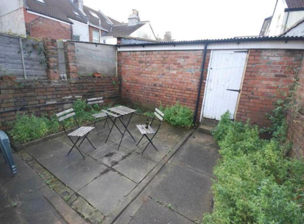 Enclosed paved rear garden with a central seati...