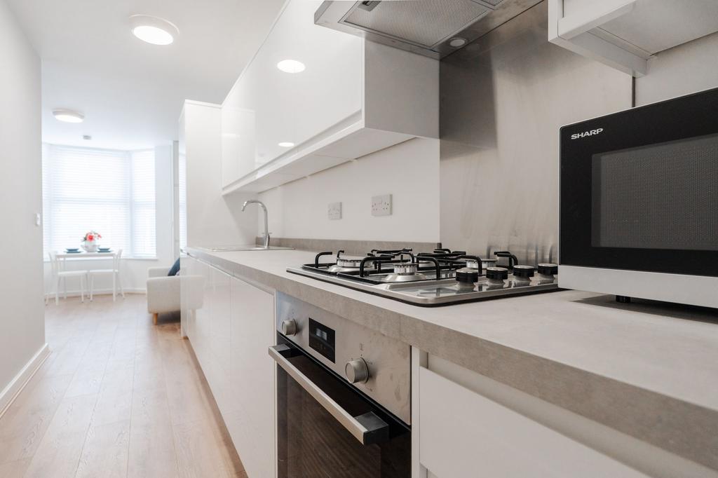 Bright modern galley kitchen with integrated ap...