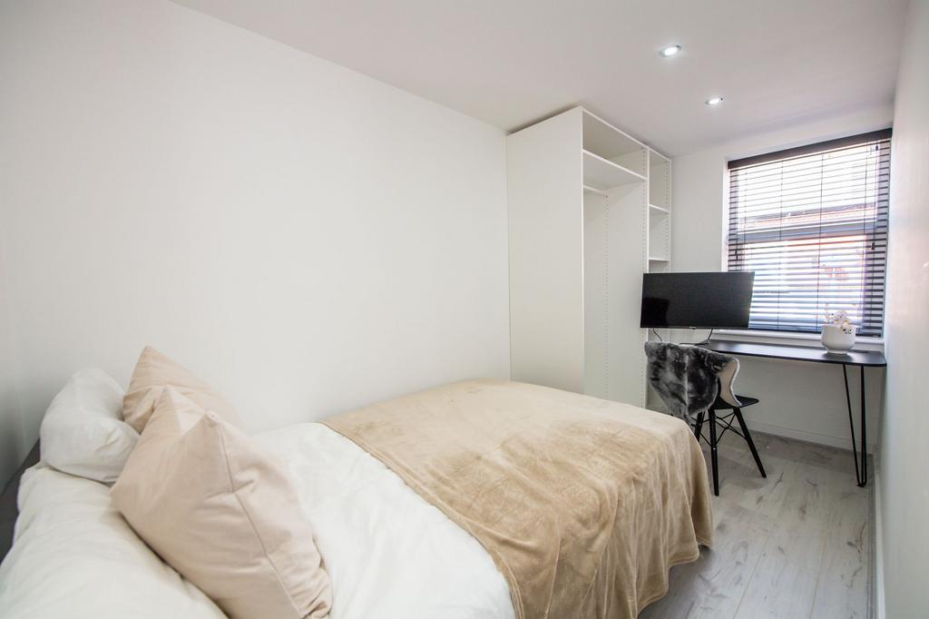 A bright and tidy bedroom featuring a comfortab...