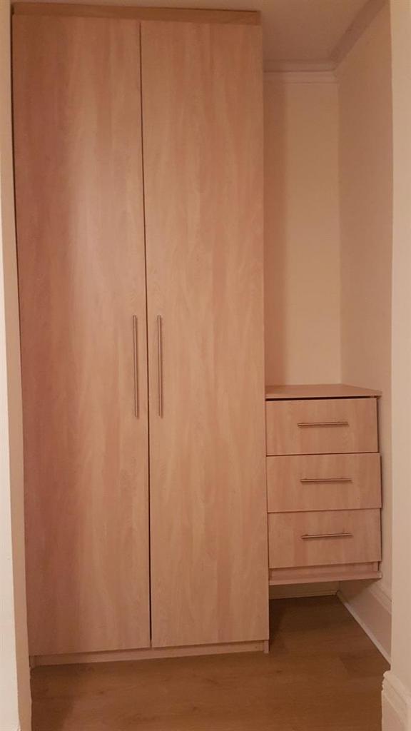 Light-wood built-in wardrobe with matching ches...