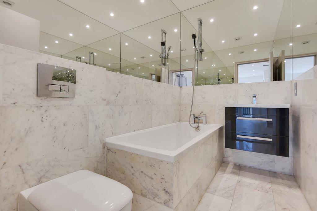 Contemporary marble-clad bathroom with a built-...
