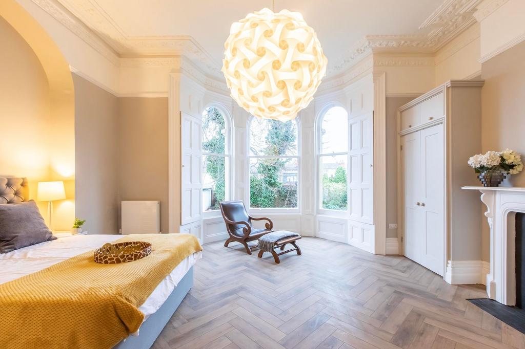 Bright, elegant bedroom with a large bay window...