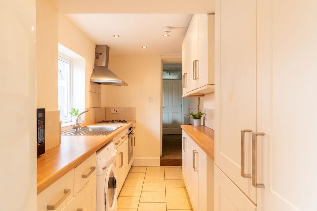 Bright, modern galley kitchen with wooden count...