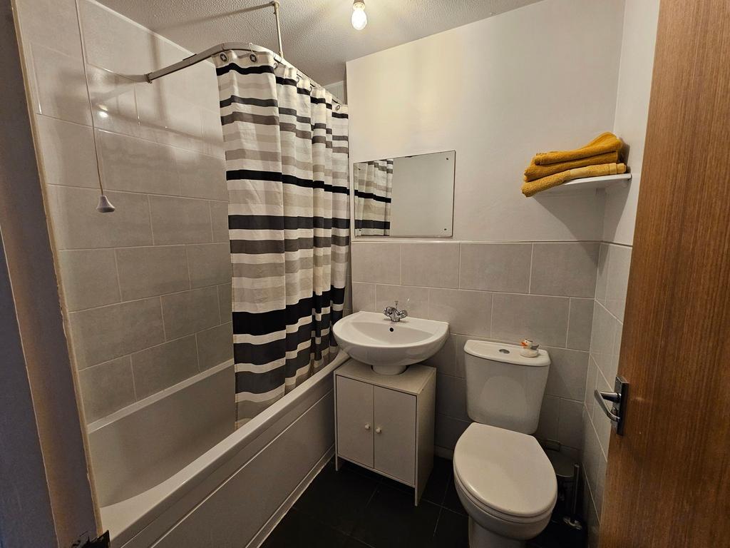 Bright, well-kept bathroom with a tiled bath an...