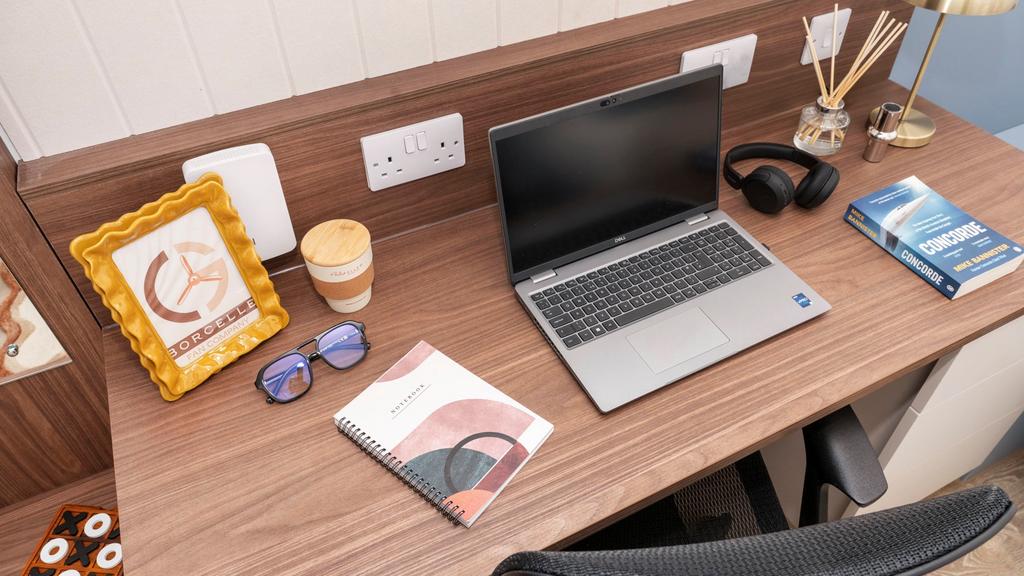 Well-appointed wooden desk with a laptop, noteb...