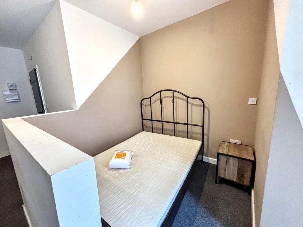 A cozy single bedroom featuring a simple metal ...
