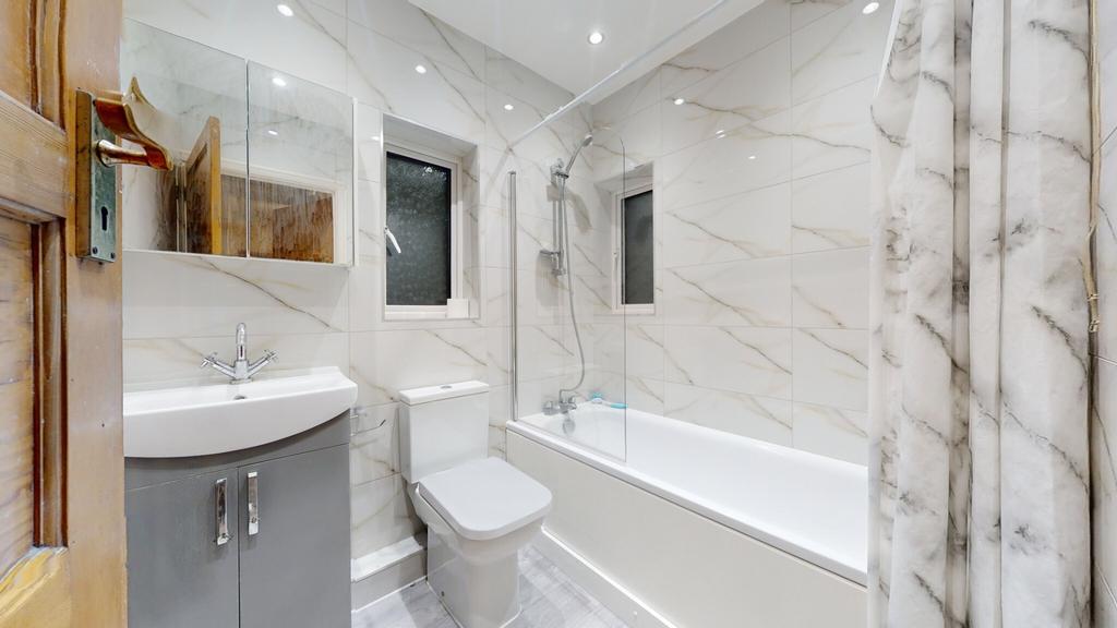 Bright, modern bathroom with a bathtub and over...