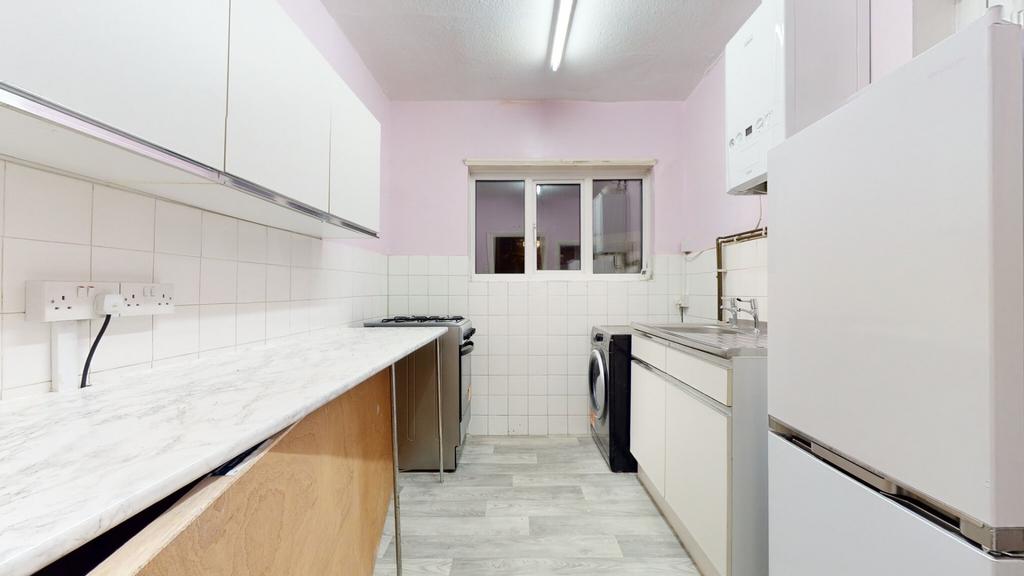 Bright galley kitchen with long marble-effect w...