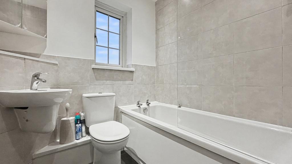 Bright, modern bathroom with a white bathtub, p...