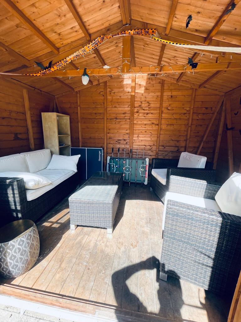 Sunny wooden garden room with comfortable ratta...