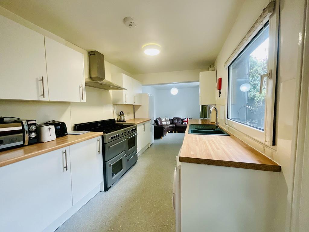 Bright, modern galley kitchen with white cabine...