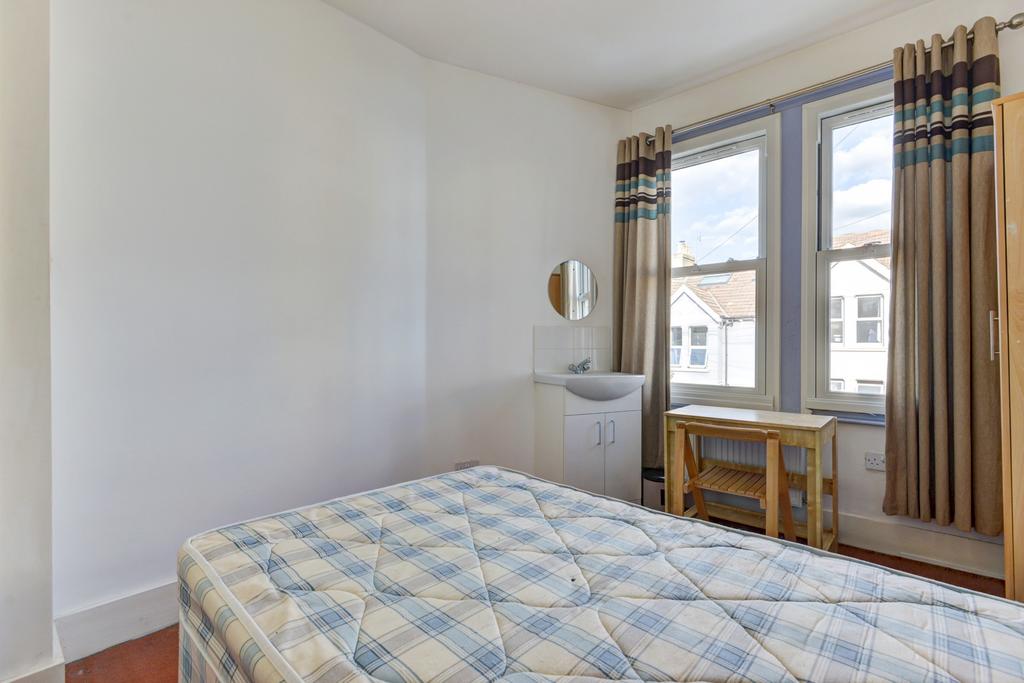 Bright bedroom with large window, simple furnis...