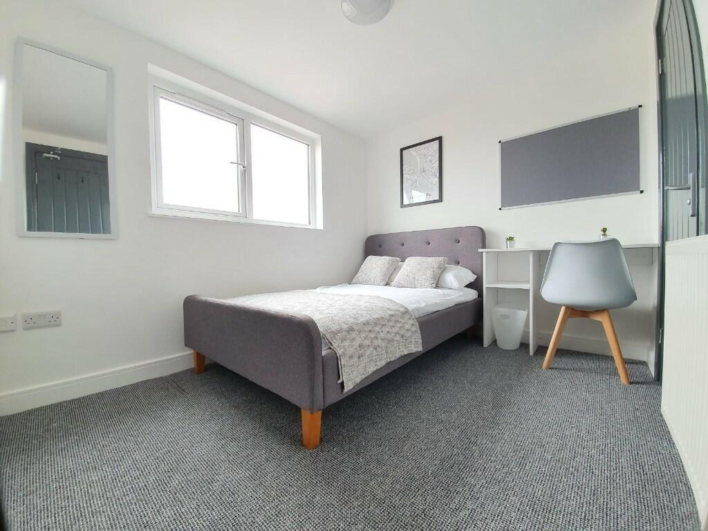 A spacious, well-lit master bedroom featuring a...
