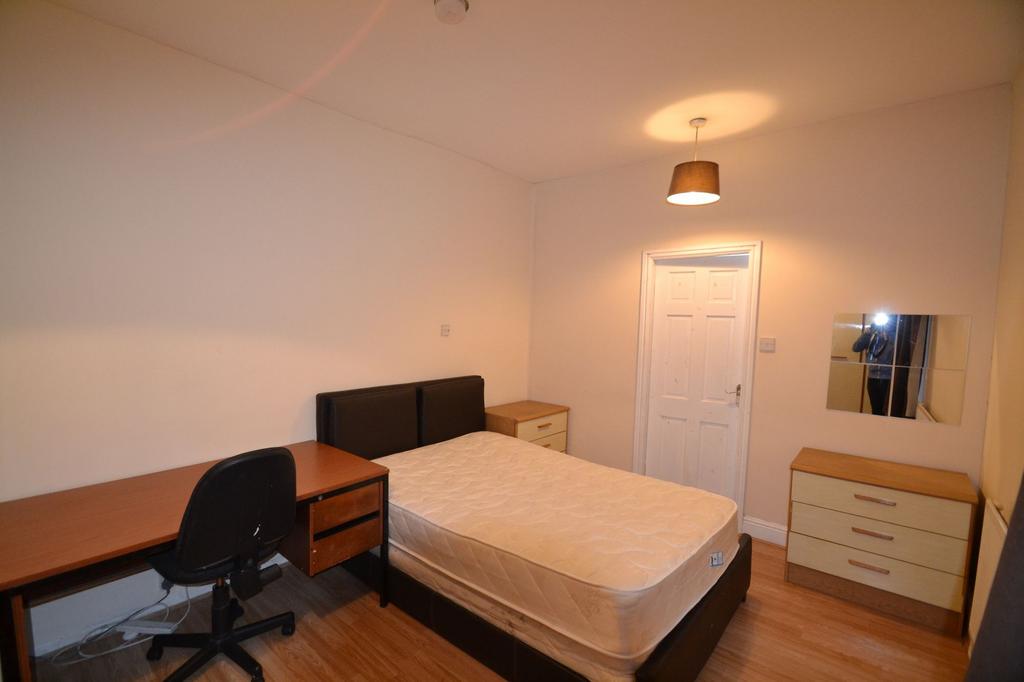 A well-lit bedroom featuring a double bed with ...