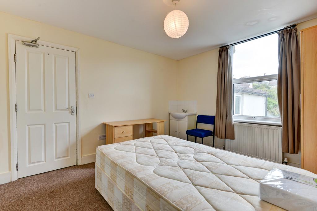 A well-lit, tidy bedroom featuring a comfortabl...