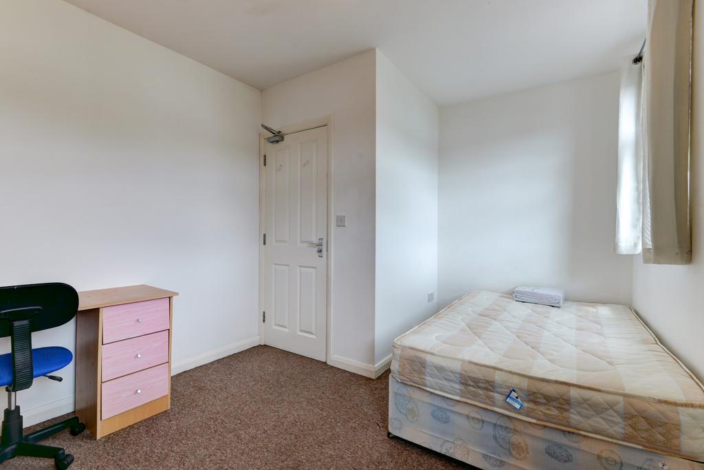 A simple bedroom featuring a single bed near th...
