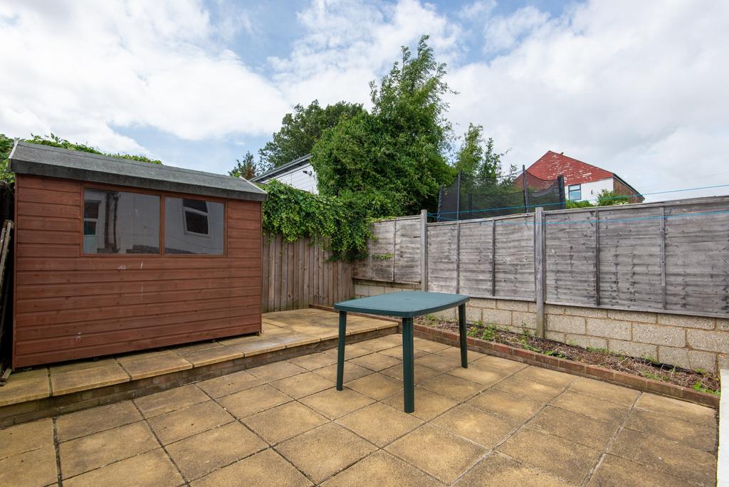 Private paved garden with a wooden storage shed...