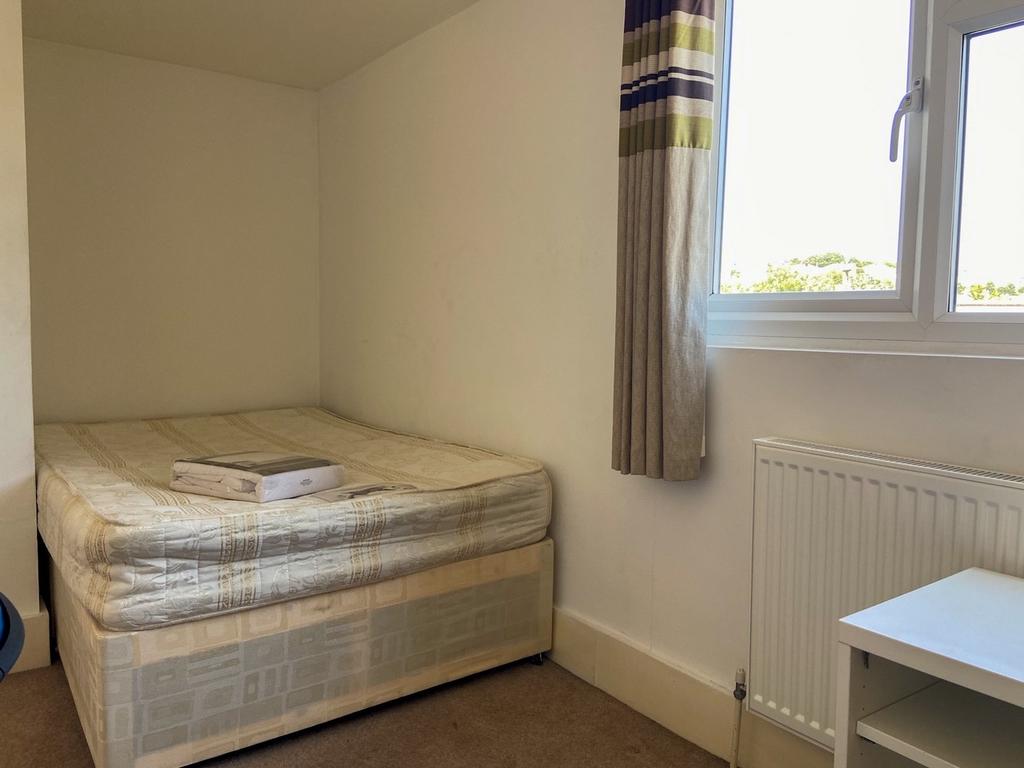 Small, tidy bedroom with a neatly made single b...