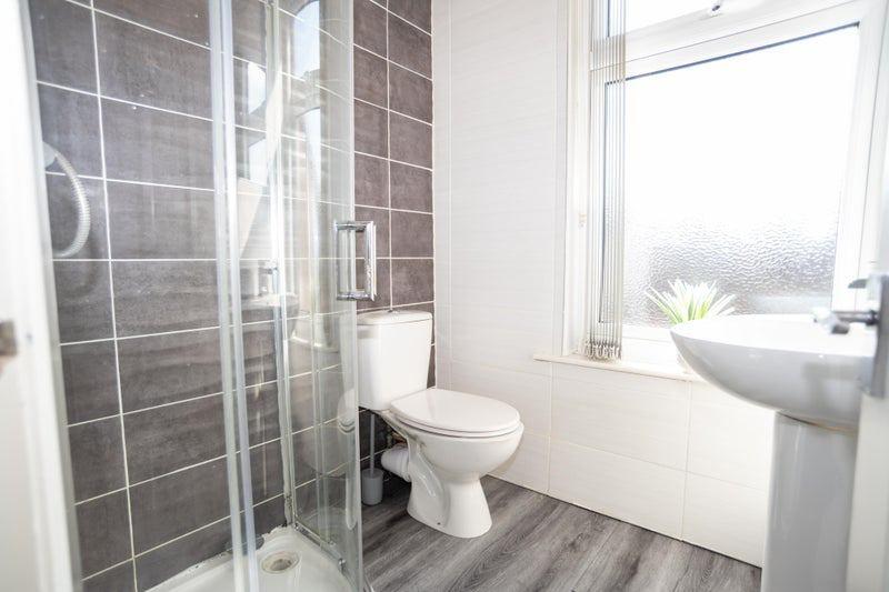Bright, modern bathroom with a corner glass sho...
