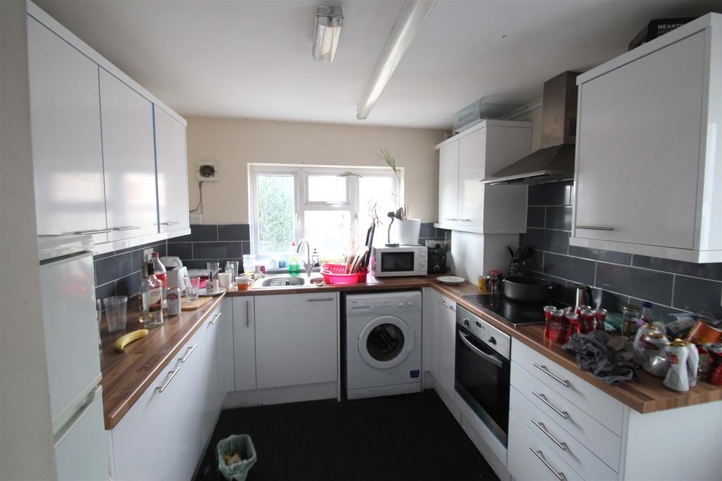 Bright galley kitchen with white cabinets, wood...