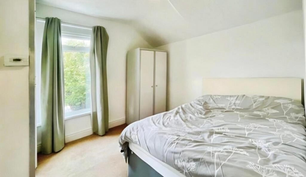 Bright double bedroom with a large window letti...