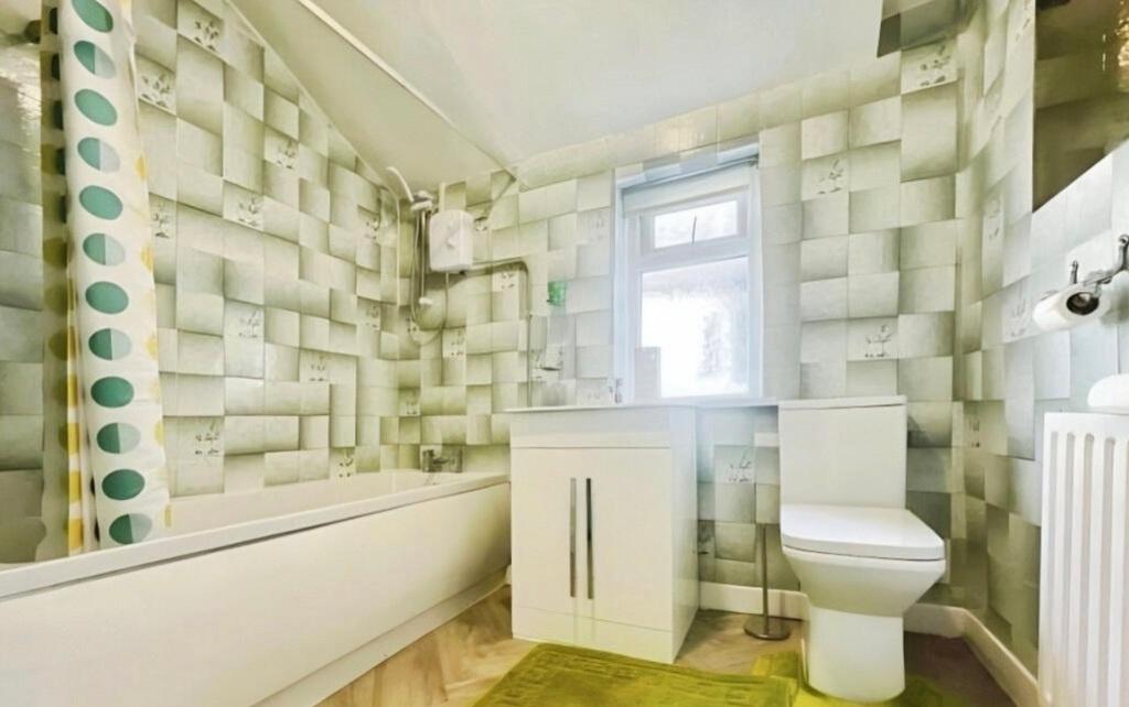 Bright, modern bathroom with patterned tiled wa...