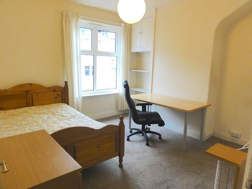 A cozy bedroom featuring two wooden beds, a win...