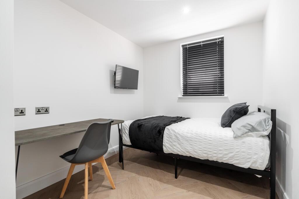A bright, clean double bedroom featuring a comf...
