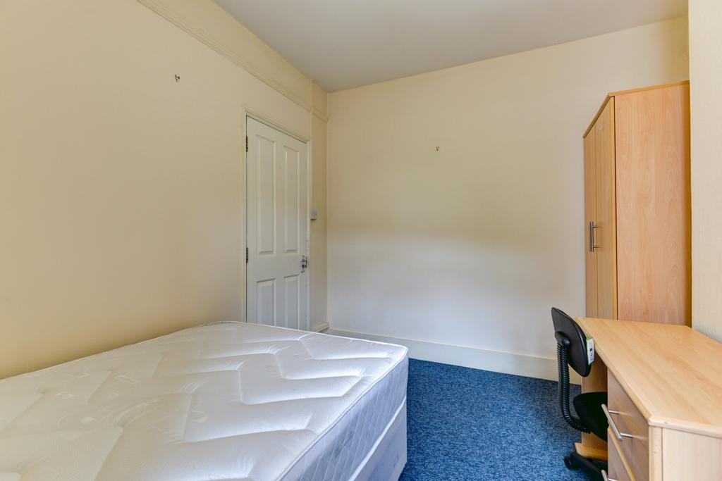 A simple student bedroom featuring a single bed...