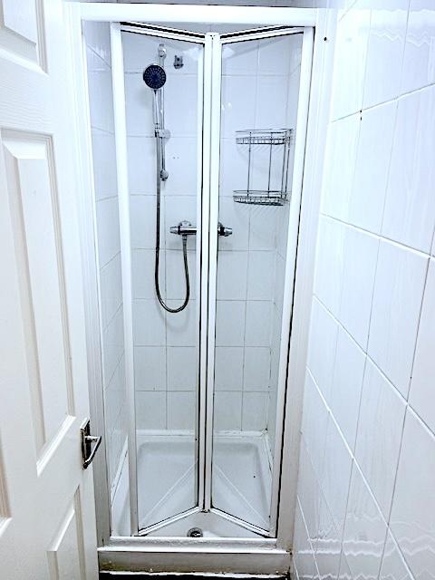 Compact tiled shower cubicle with clear folding...