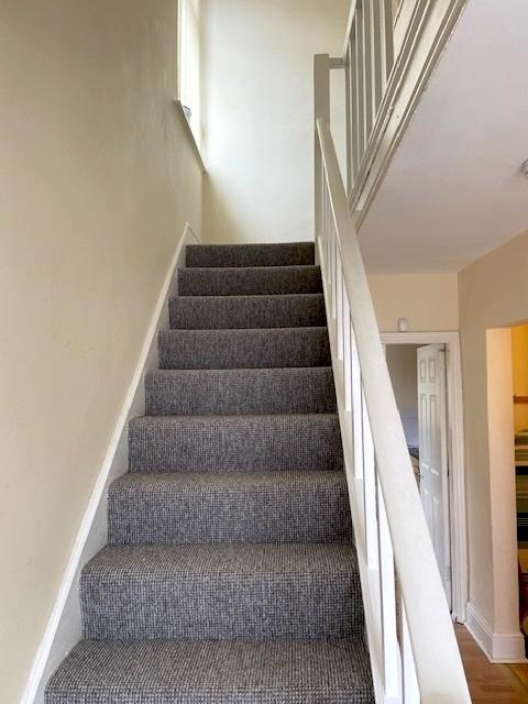 Carpeted staircase with neutral walls and white...